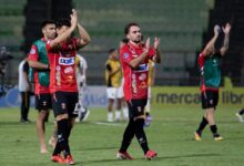 Jugadores del Caracas Fútbol Club con su uniforme principal (camiseta roja y pantalón negro) agradecen y aplauden al público sobre el terreno de juego al finalizar un partido de la CONMEBOL Sudamericana.