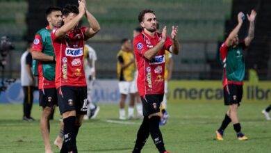 Jugadores del Caracas Fútbol Club con su uniforme principal (camiseta roja y pantalón negro) agradecen y aplauden al público sobre el terreno de juego al finalizar un partido de la CONMEBOL Sudamericana.