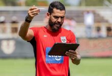 El entrenador venezolano Daniel Blanco, asistente técnico de la Selección de Panamá, de pie en un campo de entrenamiento con camiseta roja de la FEPAFUT, sosteniendo una tableta digital y un lápiz óptico mientras imparte instrucciones tácticas.