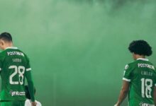 El futbolista venezolano Eduard Bello con la camiseta número 18 de Atlético Nacional de espaldas junto a su compañero Simón García (28) en la Liga BetPlay.