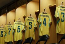 Camisetas de la selección de fútbol de Brasil colgadas en los casilleros del vestuario, destacando las dorsales de Bruno Guimarães (8), Vinícius Júnior (7), Alex Sandro (6), Casemiro (5), Marquinhos (4) y Gabriel Magalhães (3).