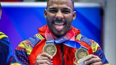 El pesista venezolano Julio Mayora sonríe con alegría y saca la lengua a la cámara mientras sostiene con ambas manos sus dos medallas de oro ganadas en los Juegos Centroamericanos y del Caribe Santo Domingo 2026.