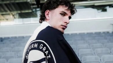 Luis Balbo de espaldas mostrando el escudo del SK Sturm Graz impreso en su chaqueta dentro del estadio