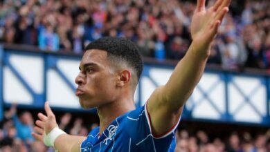 El futbolista venezolano Kevin Kelsy celebra con los brazos abiertos frente a la afición, vistiendo la camiseta azul del Rangers F.C. en el estadio de Ibrox.