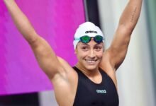 La nadadora venezolana Lismar Lyon sonríe con los brazos en alto celebrando una victoria en la piscina.